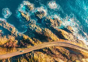 turistipercaso Aerial view of road, rocky sea shore with waves and stones at sunset in Lofoten Islands,...