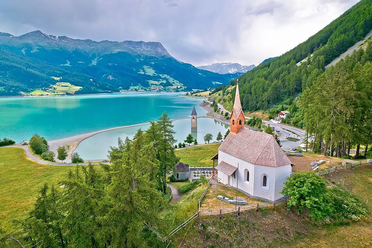 Il borgo italiano dove le campane suonano sott’acqua: la torre emerge da un lago alpino